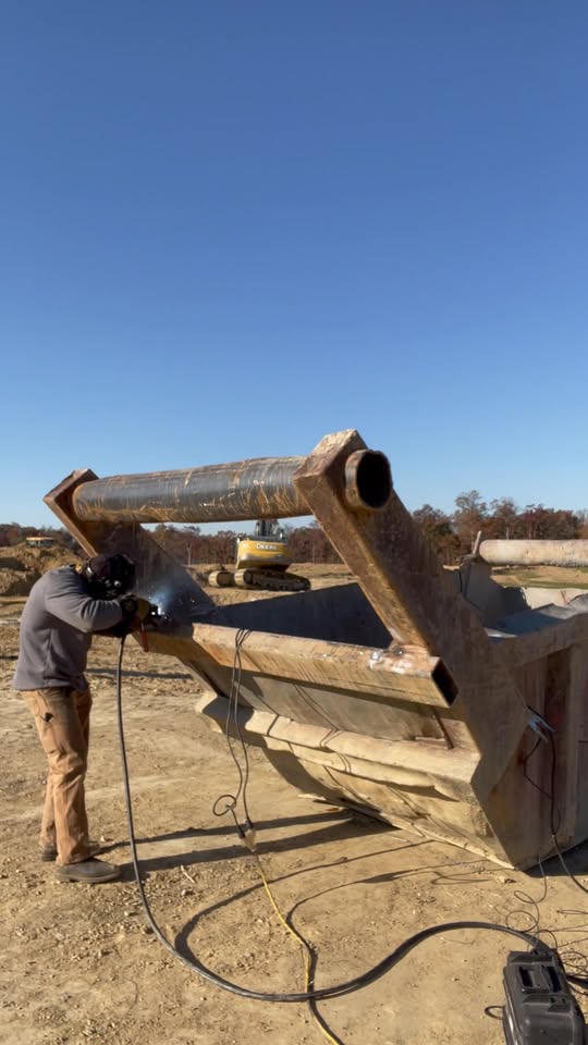 Welder working on heavy equipment at an outdoor job site